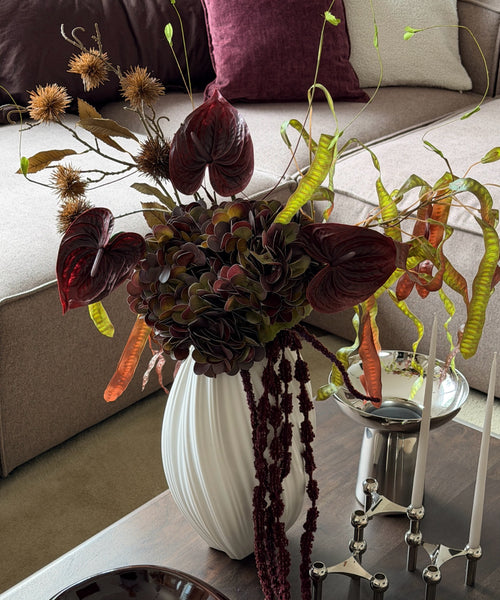 Kunstblumenstrauß Copper Dusk in Bordeaux, Grün & Kupfer aus der Serie Bloom – auf dem Couchtisch im Wohnzimmer