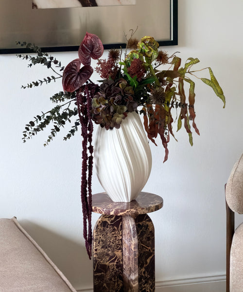 Kunstblumenstrauß Forest Ember in Bordeaux, Grün & Braun aus der Serie Bloom – auf dem Marmorsockel im Wohnzimmer