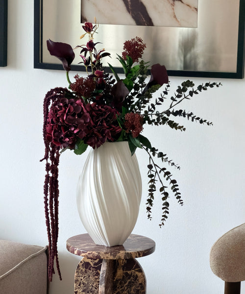Kunstblumenstrauß Merlot Night in Bordeaux & Grün aus der Serie Bloom – auf dem Marmorsockel im Wohnzimmer