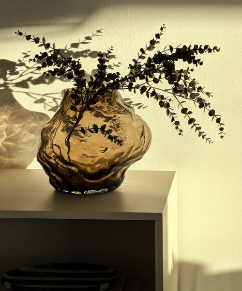Suri Vase mit Eukalyptuszweigen auf dem Sideboard im Sonnenlicht