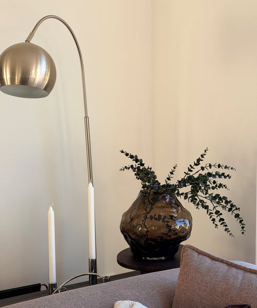Suri Vase mit Eukalyptus auf dem Beistelltisch im Wohnzimmer neben einer Bogenlampe